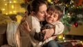 Happy cheerful mother and son playing and hugging under Christmas tree on New Year eve. Families and children Royalty Free Stock Photo