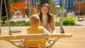 Happy cheerful mother swinging her baby son in round nest swing. Children playing outdoor, kids outside, summer holiday and Royalty Free Stock Photo