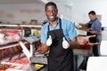 Happy African American seller of butcher store standing behind counter, giving thumbs up Royalty Free Stock Photo