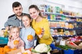 Happy family with two little girls looking for fresh oranges in supermarket Royalty Free Stock Photo
