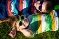 Happy cheerful smiling children, laying on a grass, wearing sunglasses, smiling at the camera, shot from above