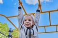 Happy cheerful and smiling Little girl 7-9 years playing on a playground, hanging walk along the monkey bars. Against Royalty Free Stock Photo