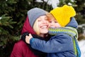 Happy cheerful smiling mother with her cute kid at snowy background. Snow-covered forest path. Winter holidays. Amazing Royalty Free Stock Photo