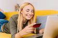 Happy cheerful smiling young blonde woman doing online shopping Royalty Free Stock Photo