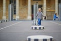 Happy cheerful toddler girl running within Columns of Buren in Palais-Royale, Paris Royalty Free Stock Photo