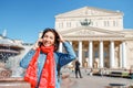 Cheerful traveler girl talking by phone at the Bolshoi Theatre in the background Royalty Free Stock Photo