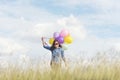 Happy cheerful woman holding colorful of balloons wear sunglasses on green meadow with cloudy blue sky. Travel Concept Royalty Free Stock Photo