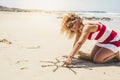 Happy cheerful woman on summer holiday vacation enjoying the beach and the outdoor designing a sun on the sand - beautiful curly Royalty Free Stock Photo