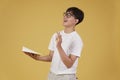 Happy cheerful young asian man student dressed casually wearing eyeglasses pointing finger up having idea isolated on yellow Royalty Free Stock Photo