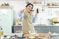 Happy cheerful young asian woman raise smartphone fist good mood wear headphones listen to music in kitchen at home Royalty Free Stock Photo