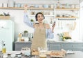 Happy cheerful young asian woman raise smartphone fist good mood wear headphones listen to music in kitchen at home Royalty Free Stock Photo