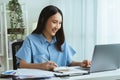 Happy cheerful young Asian woman sitting on the office with working and using on laptop computer Royalty Free Stock Photo