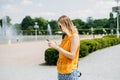 Happy cheerful young blond woman with backpack walking on city street checks her smartphone. Portrait of beautiful 30s Royalty Free Stock Photo