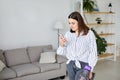 Happy cheerful young Caucasian beautiful woman vacuuming floor and using smartphone at home in living room, domestic concept Royalty Free Stock Photo