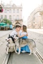 Happy cheerful young couple with two cute husky dogs walking in the city in summer sunny day. Charming young girl in Royalty Free Stock Photo