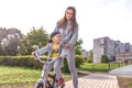 Happy cheerful Young family, little boy 3-5 years old, mother woman, learn to ride bike, in summer in city park. Weekend Royalty Free Stock Photo