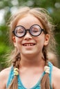 Happy cheerful young little school age girl, one single child in quirky funny big silly glasses smiling laughing, vertical Royalty Free Stock Photo