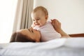 Happy cheerful young mom smiling playing with her little baby daughter lying in bed at home. Royalty Free Stock Photo