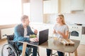 Happy cheerful young student with disability and inclusiveness eating salad and studying. He look at woman and smile Royalty Free Stock Photo