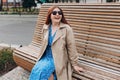 Happy cheerful young woman siting on the bench in the park on city street, Urban lifestyle concept. Traveler. Portrait Royalty Free Stock Photo