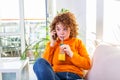 Happy cheerful young woman talking on the phone at home, smiling teen girl answering call by cellphone sitting on sofa, having Royalty Free Stock Photo