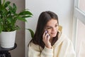 Happy cheerful young woman talking on the phone at home, smiling teenage girl answering a call on a mobile phone. Soft selective Royalty Free Stock Photo