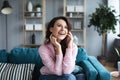 Happy cheerful young woman talking on the phone sitting on comfortable couch at home Royalty Free Stock Photo
