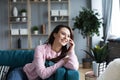 Happy cheerful young woman talking on the phone sitting on comfortable couch at home Royalty Free Stock Photo