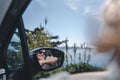 Happy cheerful young woman traveling on the sea by car. Portrait in the reflection of the rearview mirror. Summer vacation concept Royalty Free Stock Photo