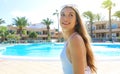 Happy cheerful young woman in white swimsuit and sunglasses on head looking side up next to swimming pool in summer vacation in Royalty Free Stock Photo