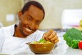 Happy chef wearing white clothes preparing bowl of food in professional kitchen, smiling while finishing last touch