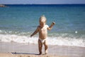 Happy child, adorable blonde toddler boy in diaper, playing on the beach running in the water, enjoying ocean on a sunny summer da