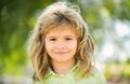 Happy child, adorable lovely kid. Joyful portrait of small child on green nature background outside. Blonde child.