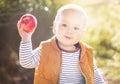 Happy child (baby boy) with red apple in the autumn (fall) day. Kid eating healthy food, snack. Royalty Free Stock Photo