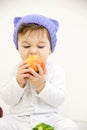 Happy child baby boy sitting in diaper and eating green apple blue eyes looking at the corner on a white Royalty Free Stock Photo