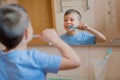Happy kid or child brushing teeth in bathroom.