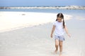 Happy child on the beach. Paradise holiday concept, girl seating on sandy beach with blue shallow water and clean sky Royalty Free Stock Photo