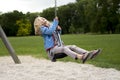 Happy Child blond girl (age 5) rids on Flying Fox play equipment in a children's playground.