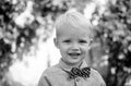 Happy child with bowtie, adorable lovely kid. Joyful portrait of small child on green nature background outside.