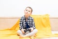 Happy child boy in checked shirt sitting on the couch with black joystick in his hands playing the video game. Playing Royalty Free Stock Photo