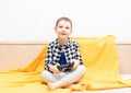 Happy child boy in checked shirt sitting on the couch with black joystick in his hands playing the video game. Playing Royalty Free Stock Photo