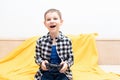 Happy child boy in checked shirt sitting on the couch with black joystick in his hands playing the video game. Playing Royalty Free Stock Photo