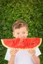 Happy child boy is eating a red juicy, tasty watermelon. Caucasian kid smiling and having fun. Concept of healthy food.