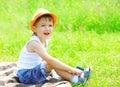 Happy child boy in hat sitting on grass in summer Royalty Free Stock Photo