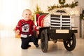 Happy child boy is playing with the children`s toy car on background of the Christmas tree. Royalty Free Stock Photo