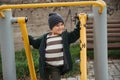 Happy child boy playing on horizontal bars on playground in autumn