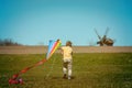 Happy child boy playing with a kite on meadow in summer in nature. Kid running on green field with colorful kite Royalty Free Stock Photo
