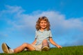 Happy child boy sitting on green grass outdoors in spring park. Royalty Free Stock Photo