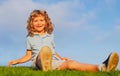 Happy child boy sitting on green grass outdoors in summer park. Royalty Free Stock Photo
