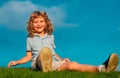 Happy child boy sitting on green grass outdoors in summer park. Royalty Free Stock Photo